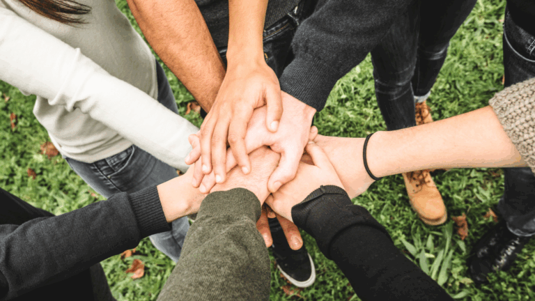 Volontari che formano un team aziendale e che uniscono le mani in segno di unione e solidarietà per fare un'attività di volontariato